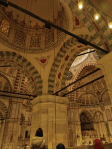 Interior dome and arches of the Fatih Mosque in Istanbul, adorned with intricate Ottoman calligraphy and geometric patterns.